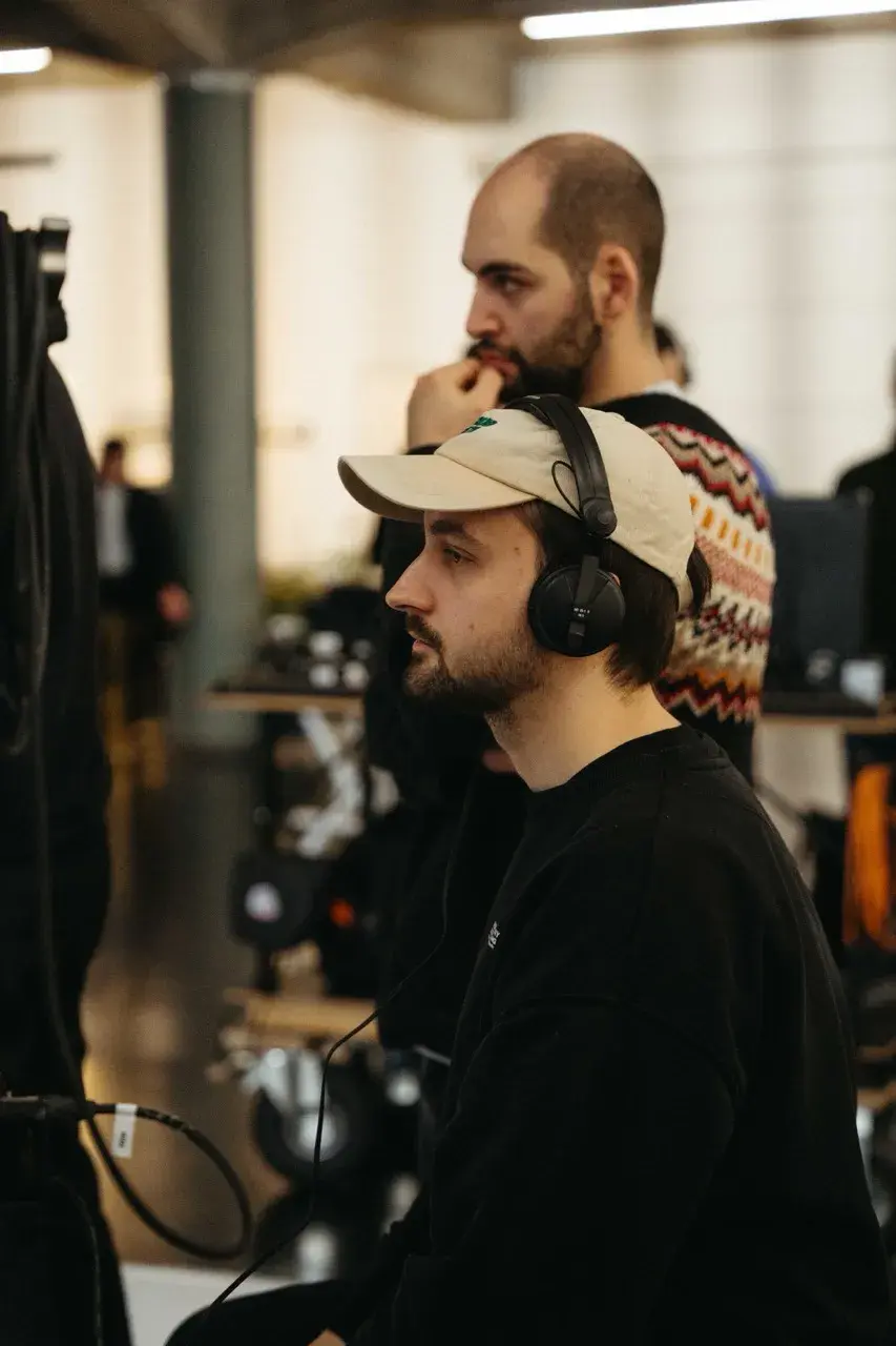 DoP Munir Werner and producer Marius Hoppe wearing headphones and a cap, monitoring audio on the set of the FDP TV commercial for the 2025 federal election.
