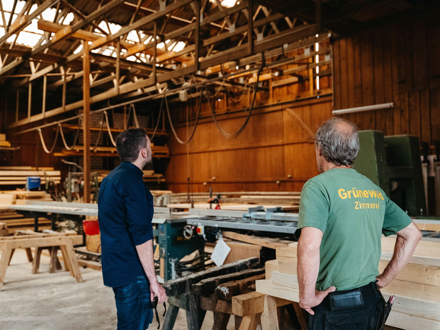 Konstantin Kuhle and a carpenter observing the roof structure inside a traditional workshop.