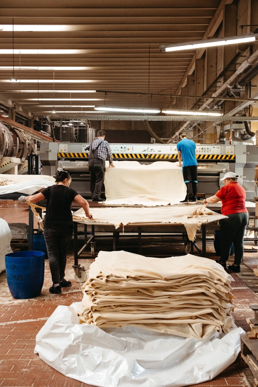 View into a large production hall of the leather industry, where employees sort hides and operate machines.