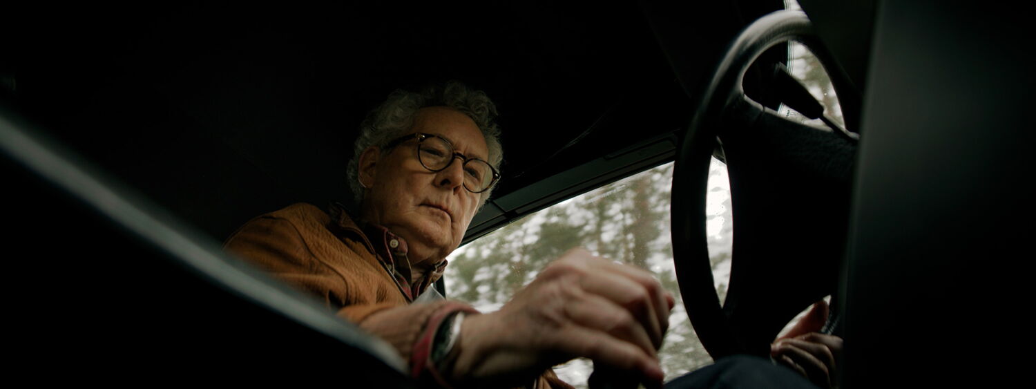 Interior low-angle shot: The driver shifting gears in the classic Saab convertible while driving.