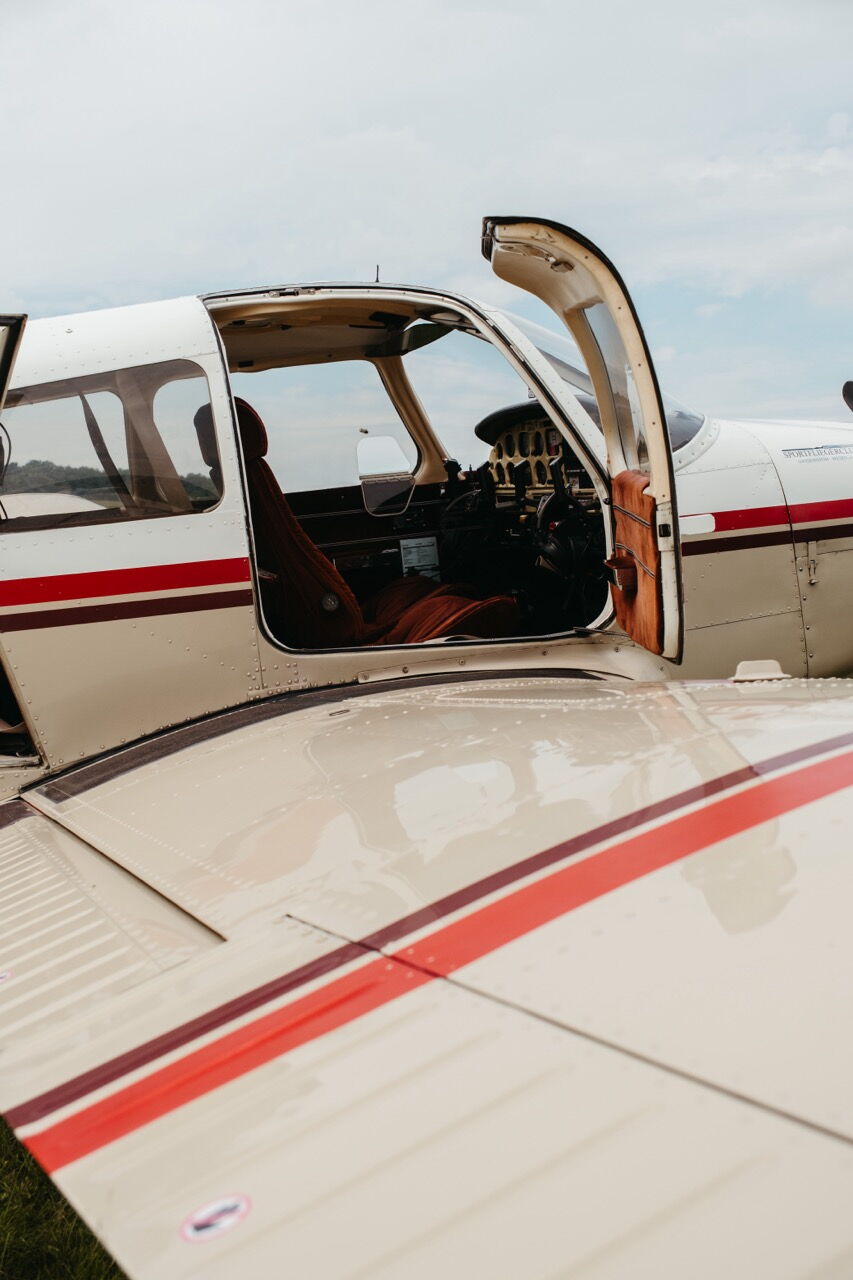 View into the cockpit and interior of a small propeller plane with the door open.
