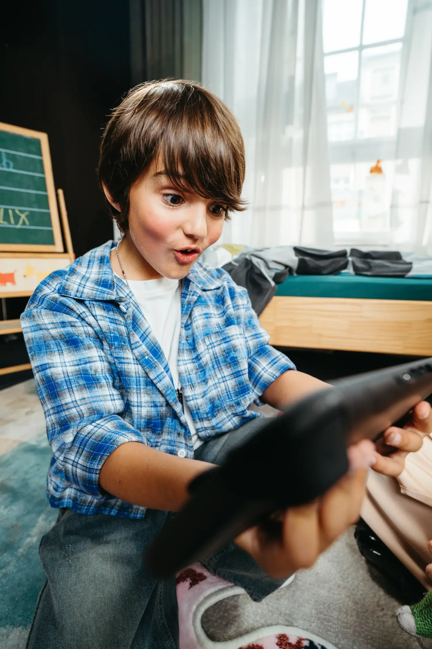 Close-up of a boy looking surprised and excited at his handheld gaming console. Scene from the SHEIN Kids commercial.