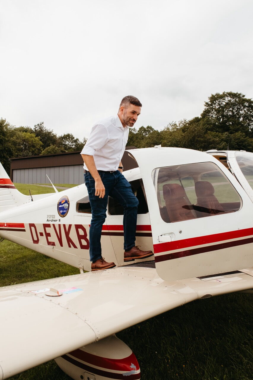 Konstantin Kuhle boarding a small sports aircraft via the wing to survey his constituency from the air.