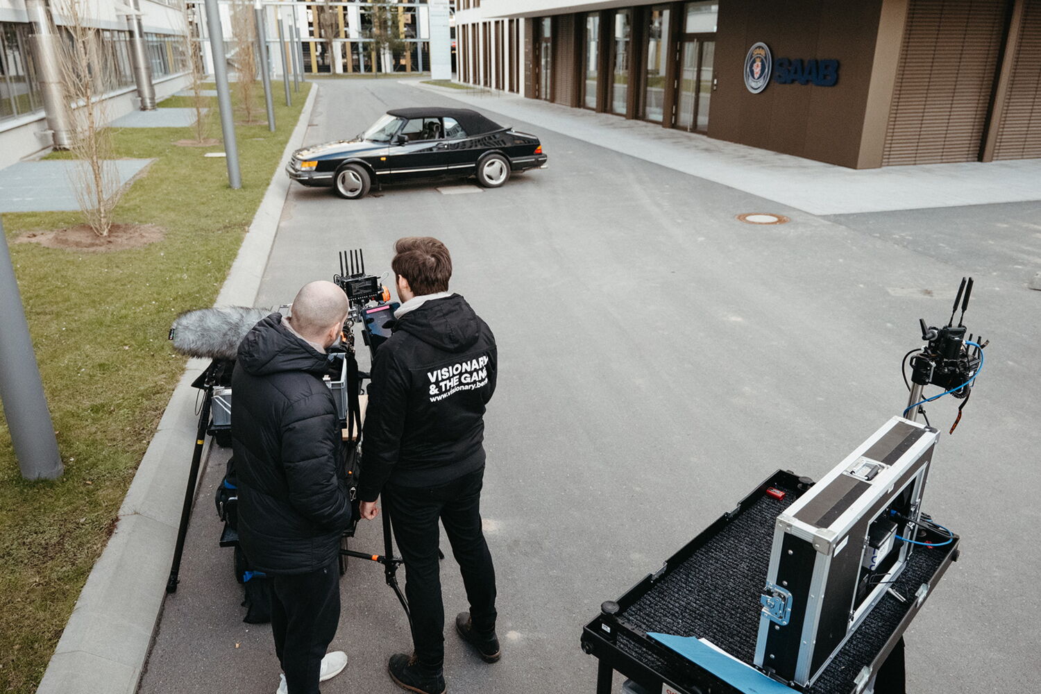 Director Munir Werner and production team Marius Hoppe discussing the next scene in front of the Saab building with the black vintage car in the background.