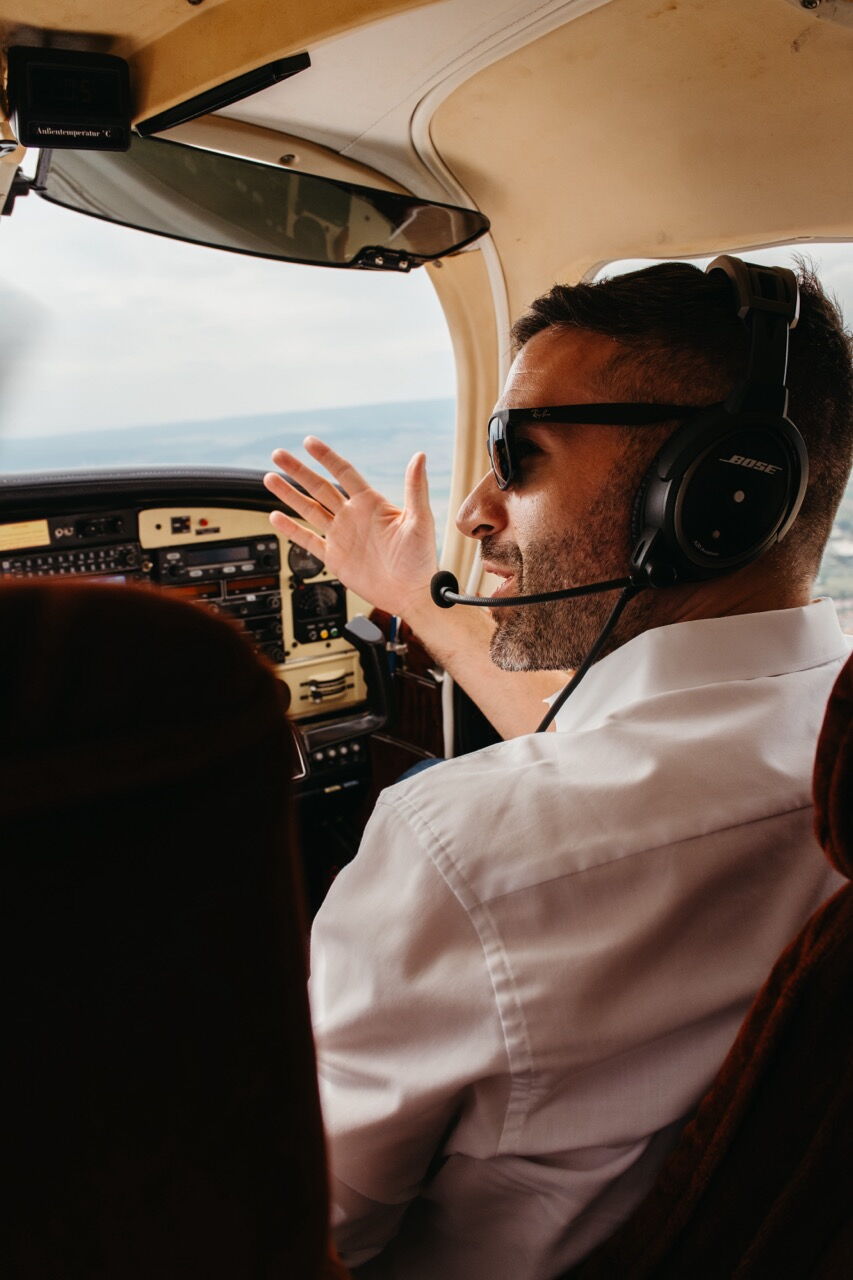 Konstantin Kuhle sitting in the cockpit of a plane wearing a headset and sunglasses, talking during the flight.