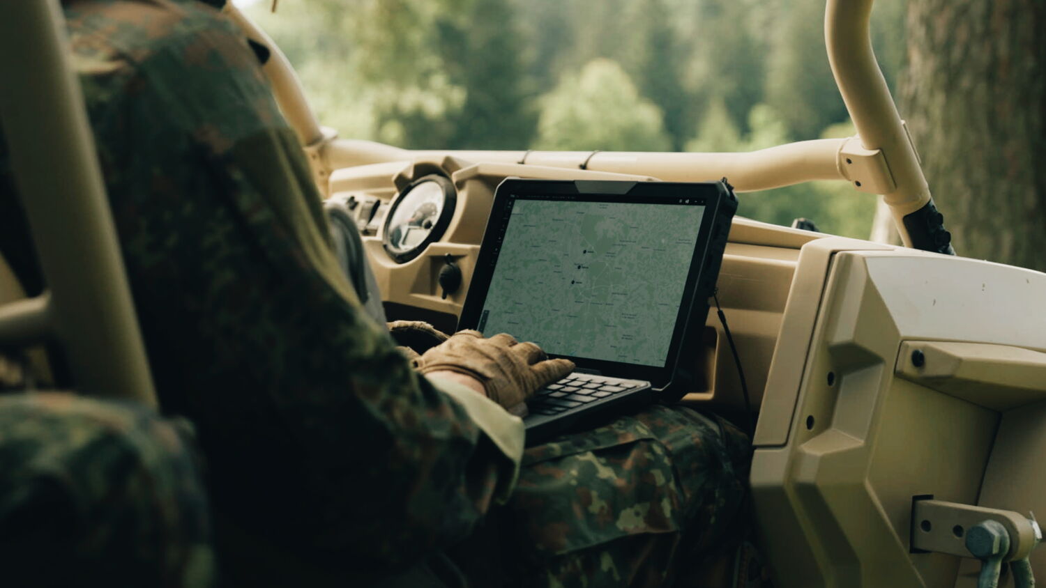 Nahaufnahme (Over-Shoulder) eines Soldaten im Fahrzeug, der Daten auf einem robusten Tablet verarbeitet – Teil des vernetzten Saab L20C Systems.