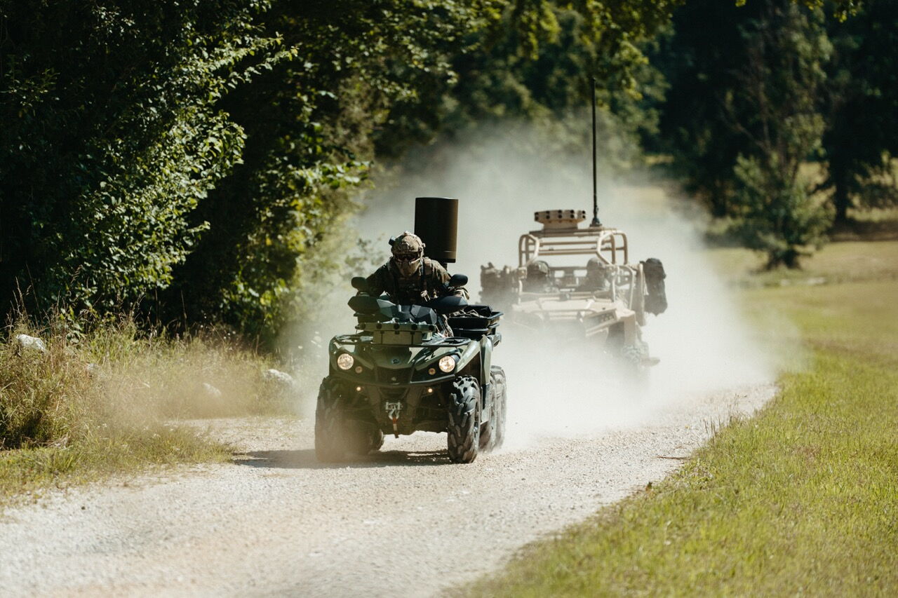 Ein militärisches Geländefahrzeug (ATV) fährt durch eine Staubwolke, ausgestattet mit dem Saab Sirius Compact L20C Sensor zur elektronischen Aufklärung.