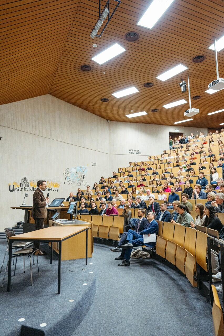 Wide shot of a well-filled large lecture hall during a discussion event with Konstantin Kuhle.