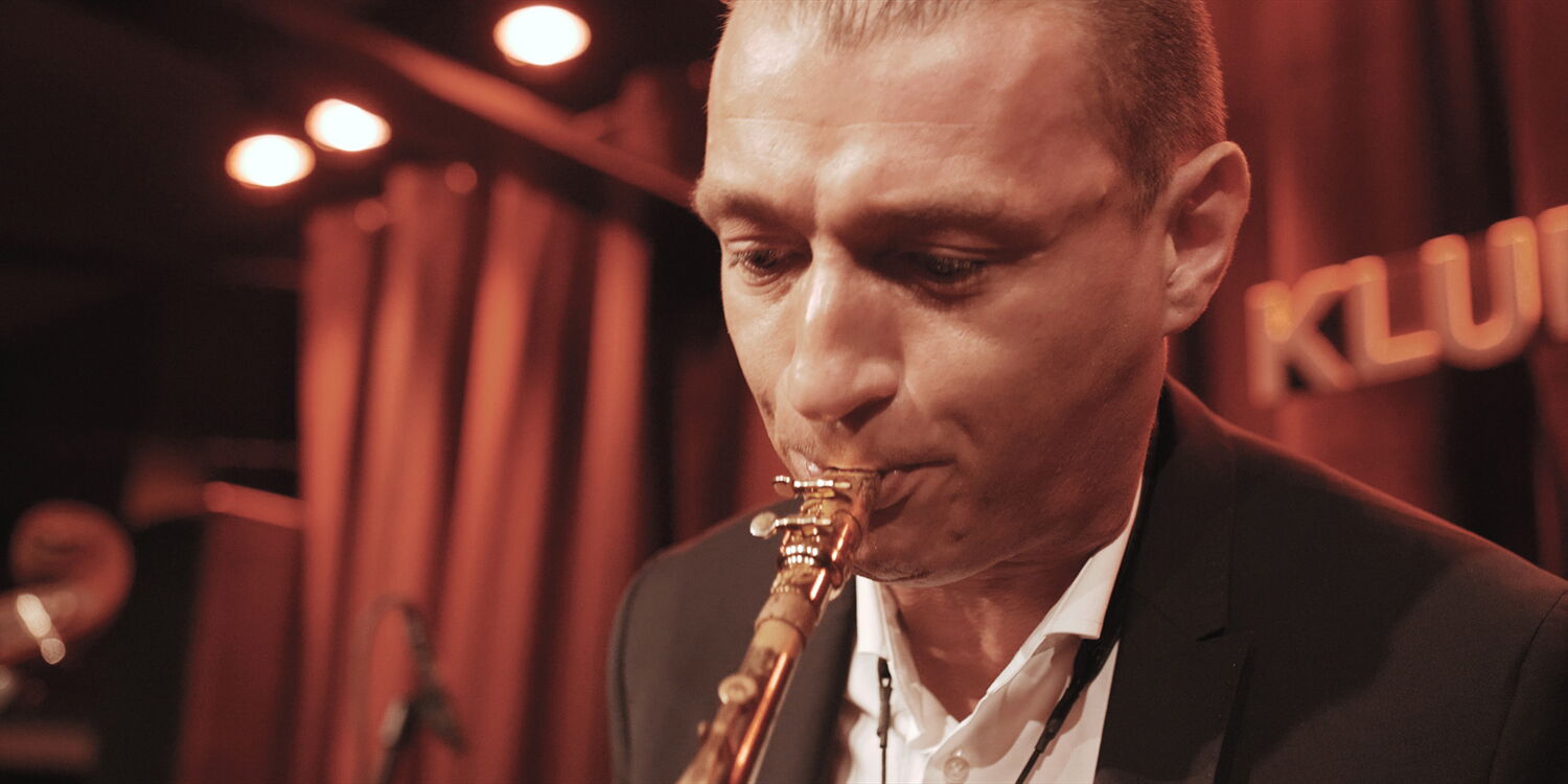 Emotional close-up of a saxophonist during an intense solo in the warm stage light of Orange Sunday.
