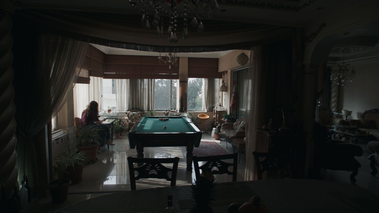 An activist sitting alone in her apartment in Beirut – a quiet, dark scene contrasting with the political unrest outside.