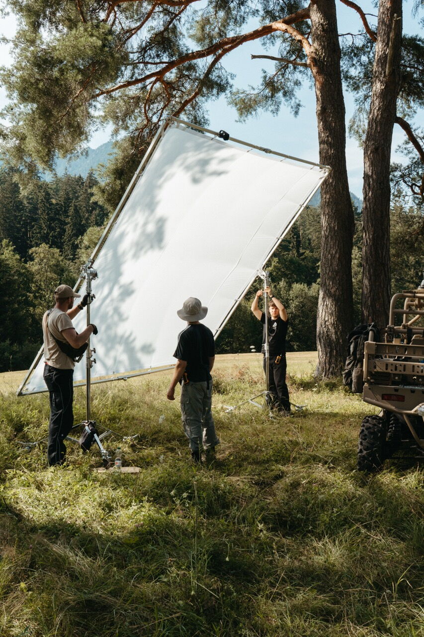 Behind the Scenes: Die Crew positioniert einen großen Diffusor-Rahmen im Wald, um das Sonnenlicht für den Saab Werbespot weicher zu gestalten.