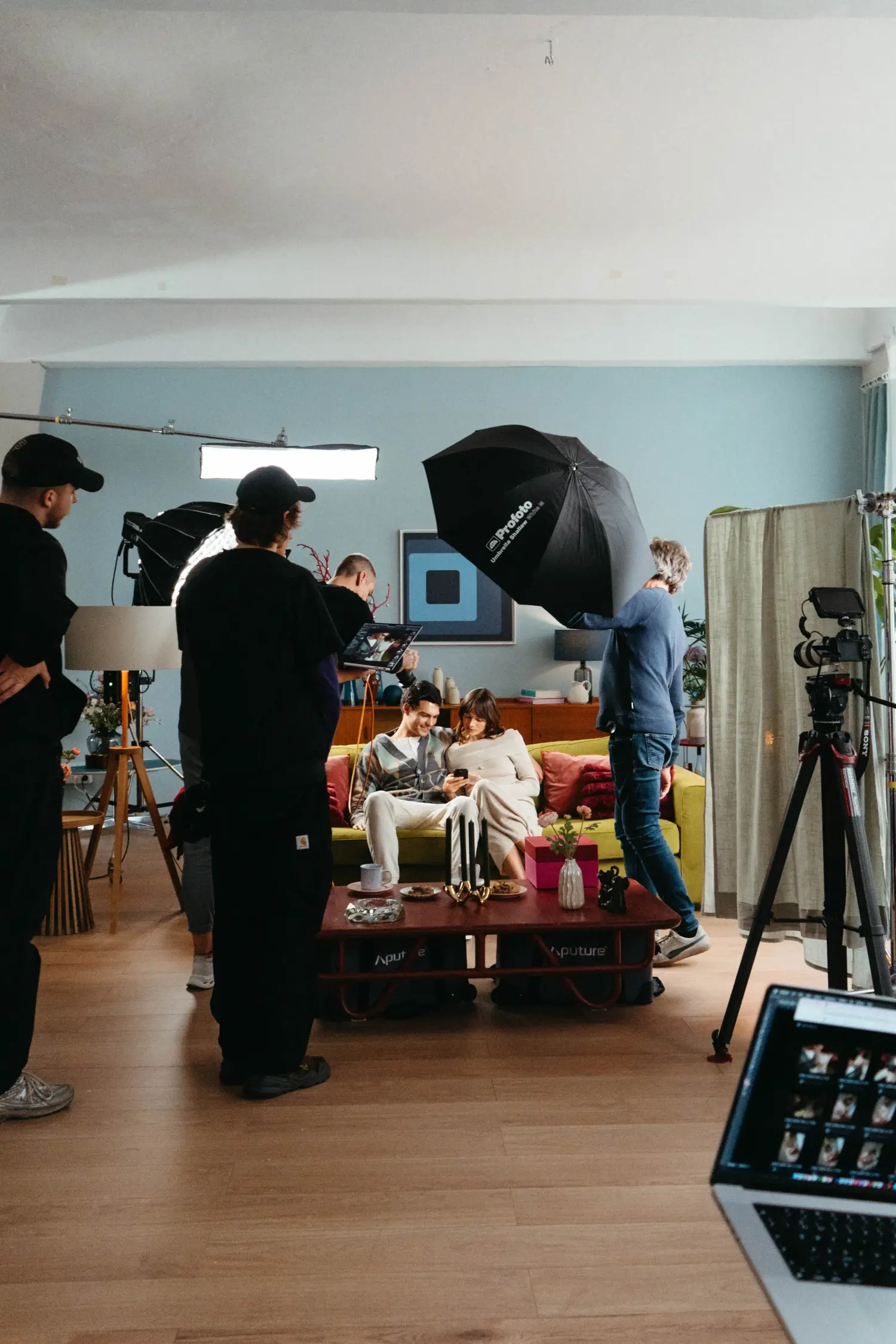 Behind the scenes in the living room set: Gaffers adjusting a large softbox for a scene with a couple on the sofa.