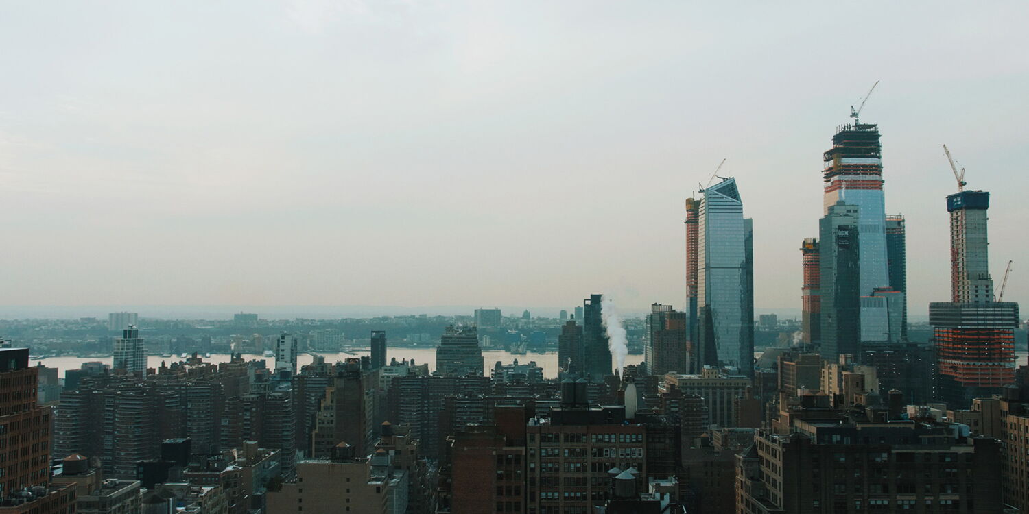 Wide-angle shot of the New York City skyline featuring modern skyscrapers on a cloudy day.