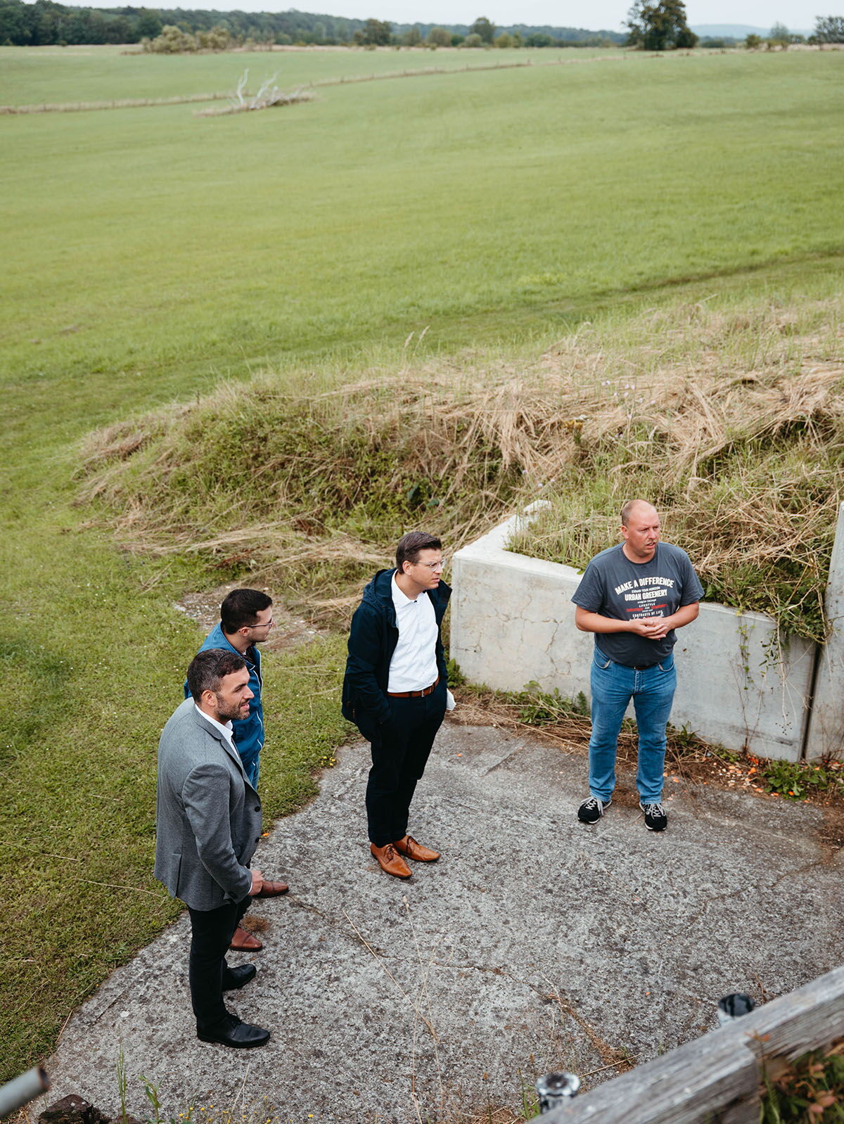 Konstantin Kuhle and a visiting group in conversation with a resident in front of a building in a rural area.