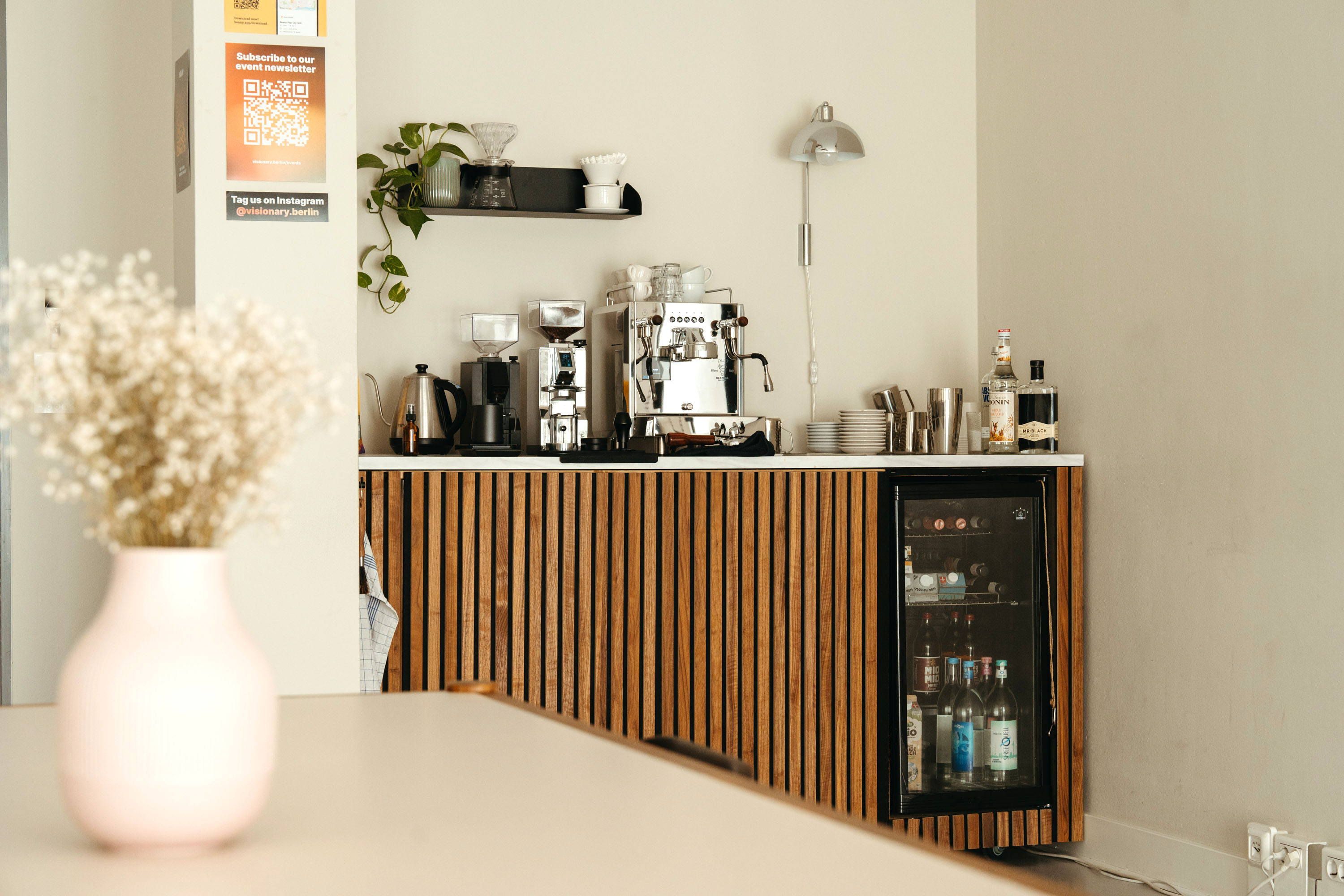 The stylish coffee bar and kitchenette at Visionary Berlin's rental studio, featuring a professional espresso machine, mini-fridge, and pour-over coffee station.