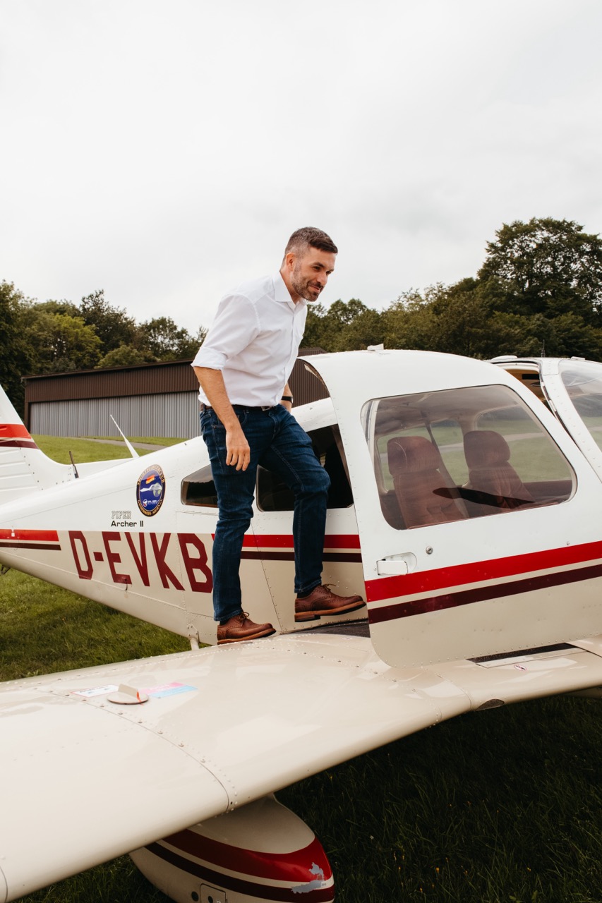 Konstantin Kuhle steigt über die Tragfläche in ein kleines Sportflugzeug ein, um seinen Wahlkreis aus der Luft zu besichtigen.