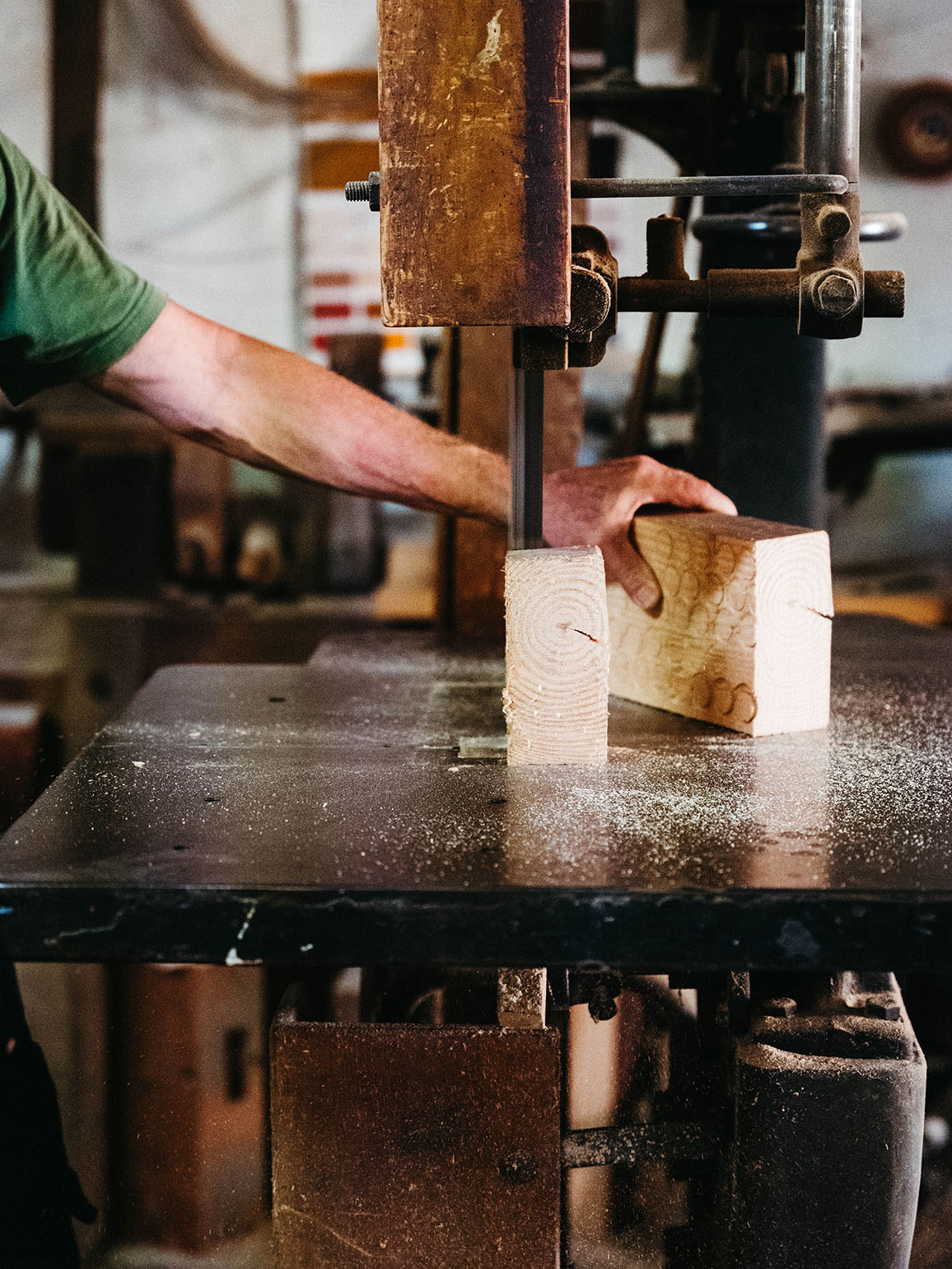 Close-up: A craftsman precisely sawing a block of wood on a bandsaw at Grünewald carpentry.
