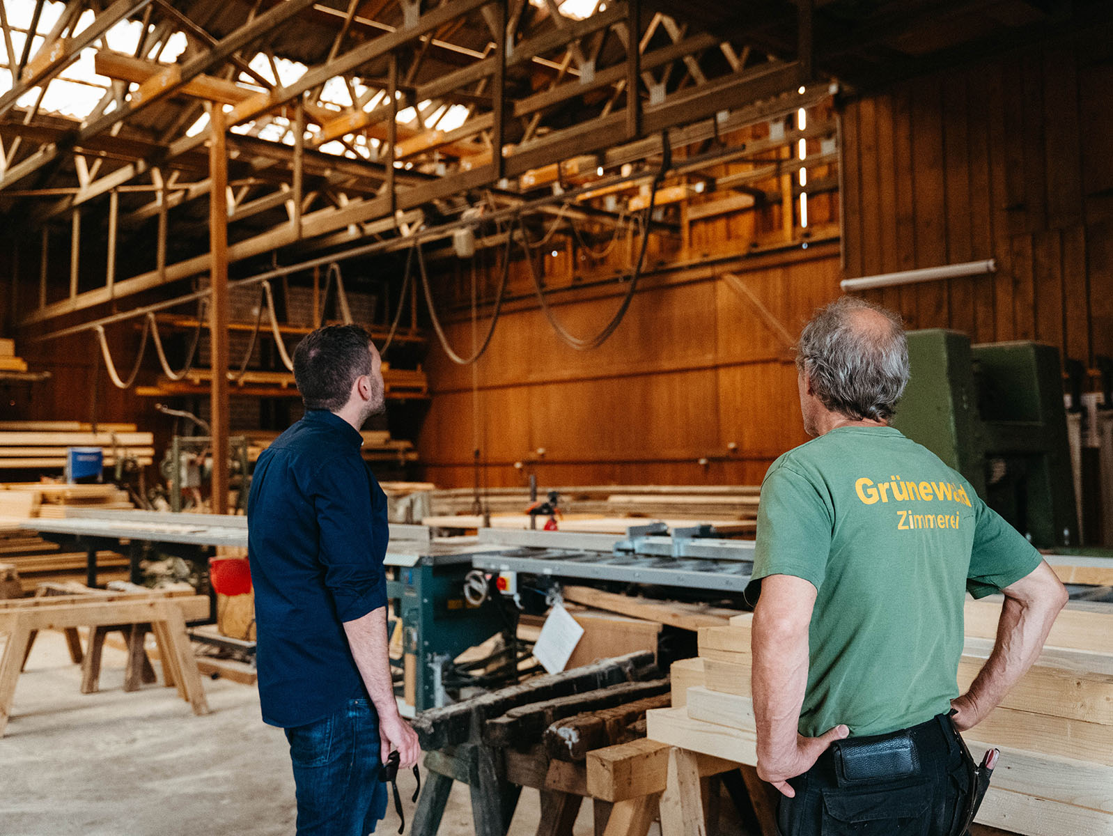 Konstantin Kuhle und ein Zimmermann betrachten die Dachkonstruktion in einer traditionellen Werkstatt.
